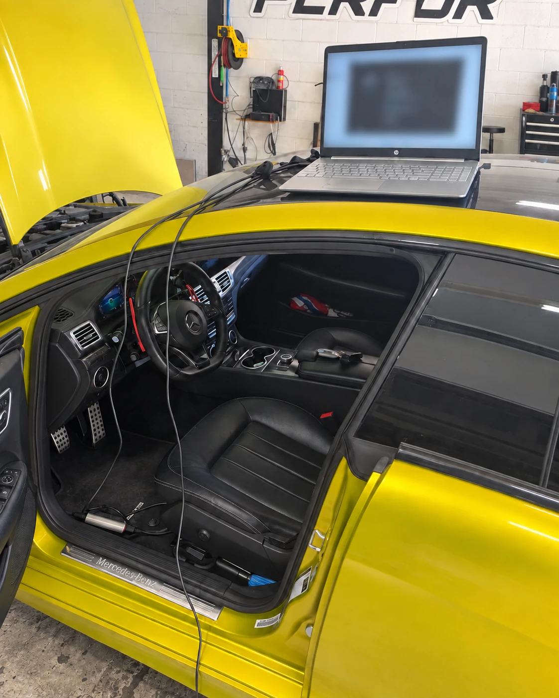 Yellow Mercedes with a laptop and tuning cables in the Cedar Performance workshop