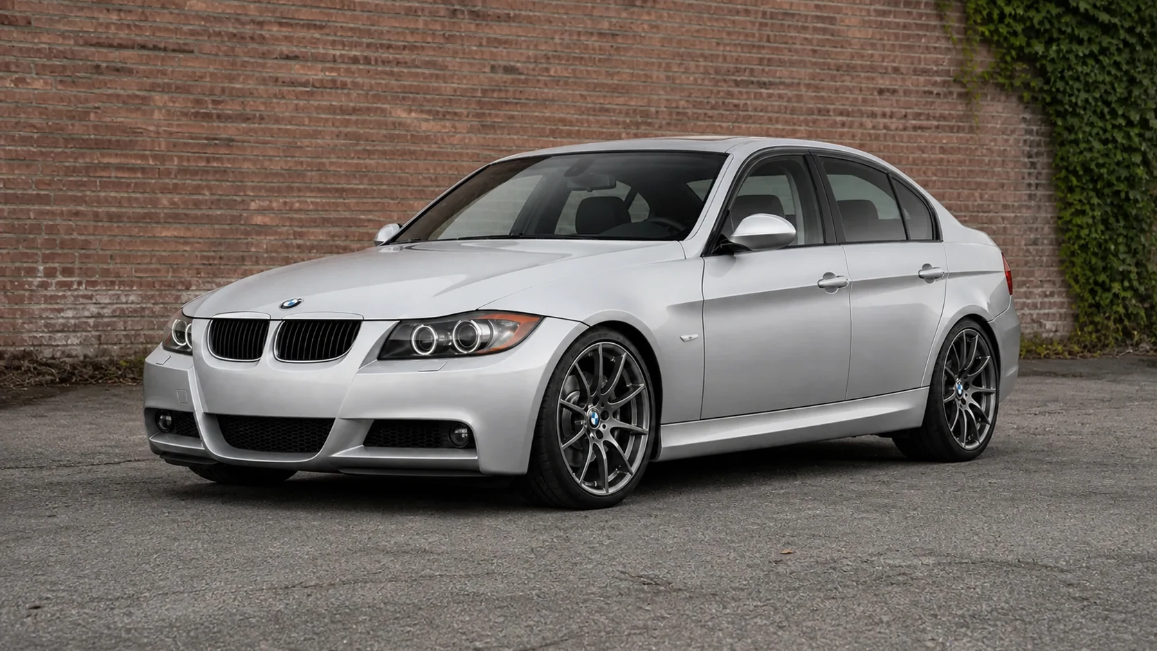 Silver E90 BMW 3 Series sedan beside a brick wall