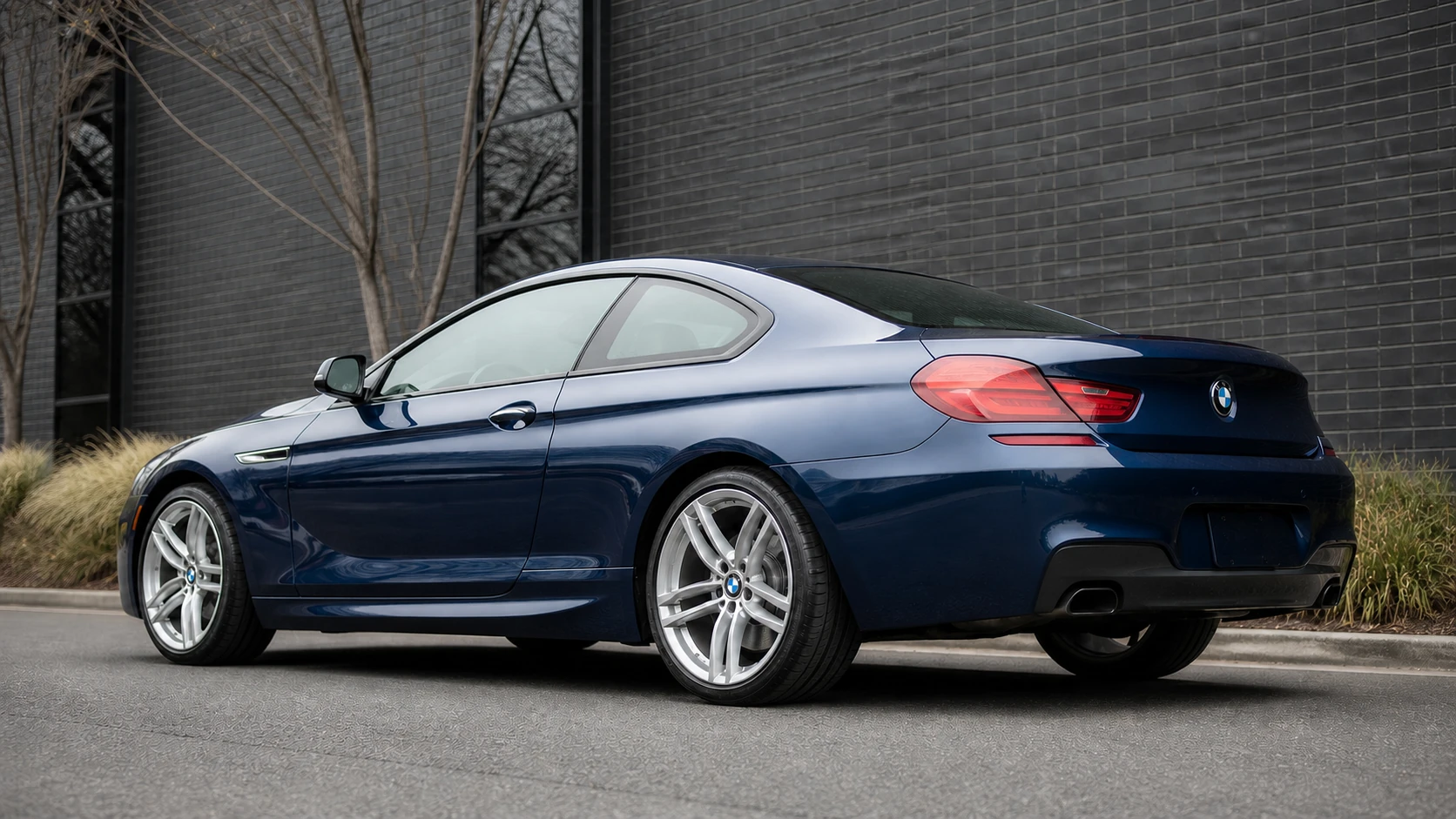 Blue F13 BMW 6 Series coupe outside a dark brick industrial building