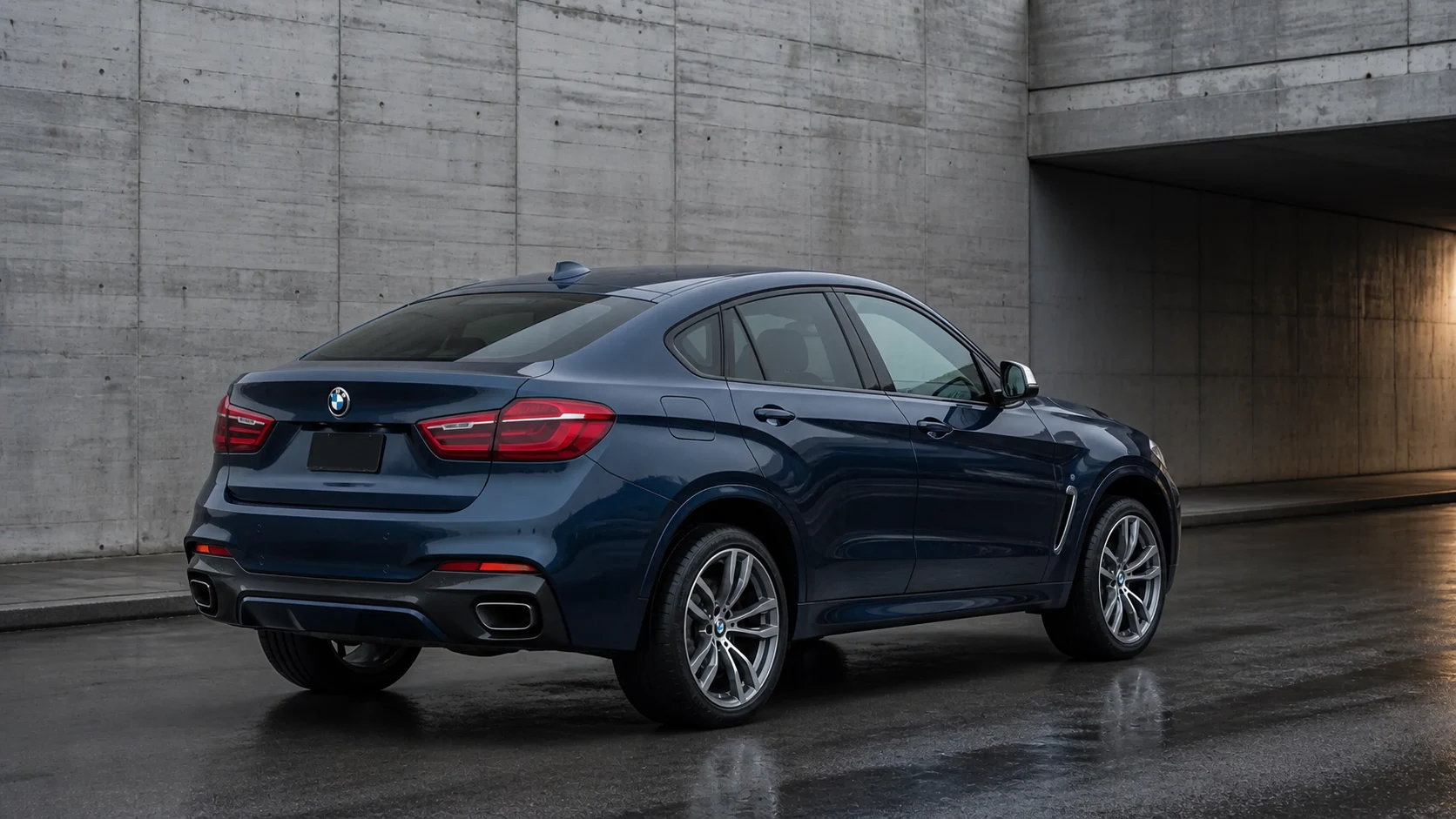 Dark blue F16 BMW X6 in a low rear three-quarter view on wet concrete beneath an underpass