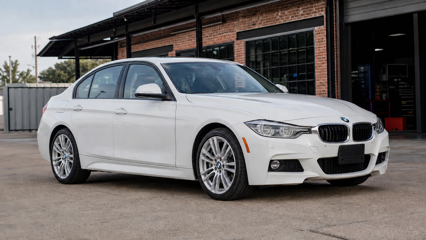 White F30 BMW four-cylinder sedan outside an independent performance shop