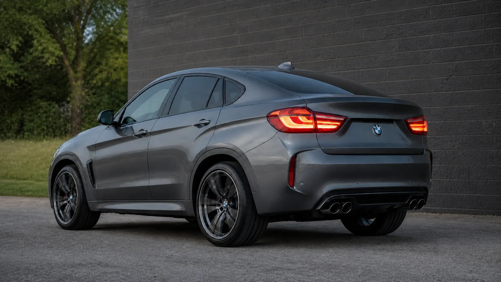 Gray F86 BMW X6 M parked beside a locality-neutral masonry wall