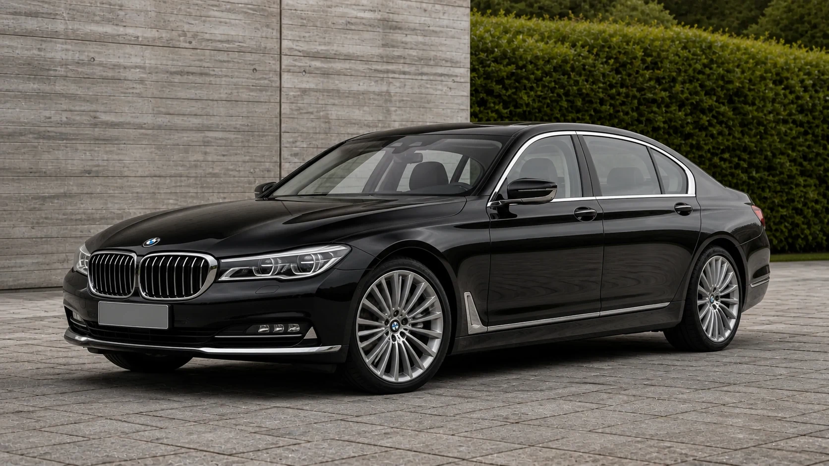 Black pre-LCI G11 BMW 7 Series sedan beside a board-formed concrete wall
