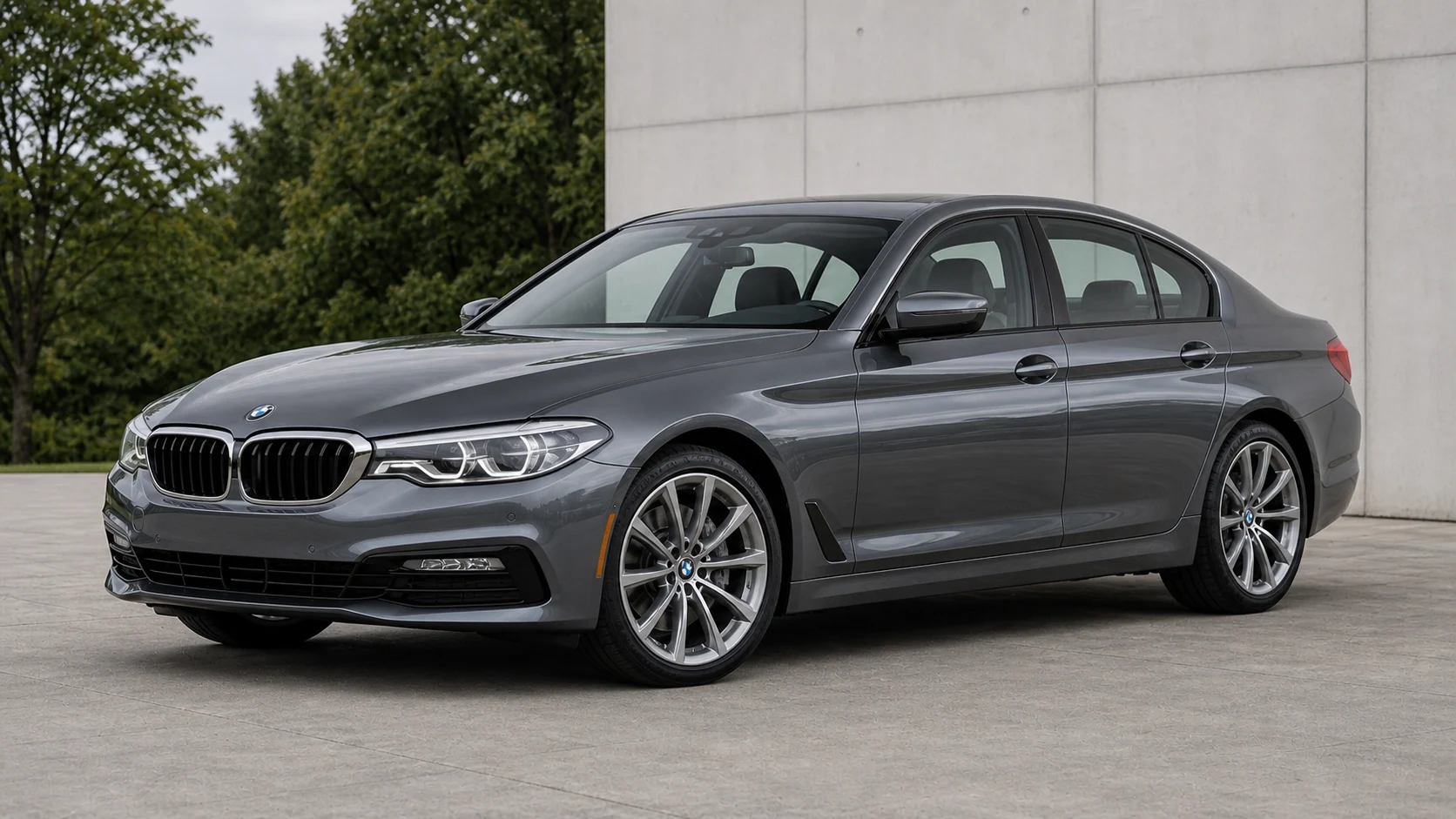 Dark gray pre-LCI G30 BMW 5 Series sedan beside a concrete wall
