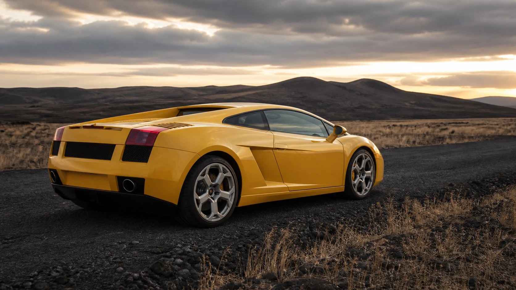 Yellow Lamborghini Gallardo in a rear three-quarter view on an upland road