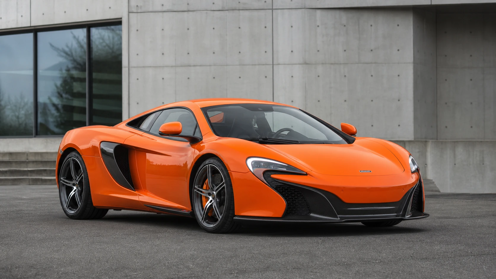 Orange McLaren 650S outside a modern concrete building