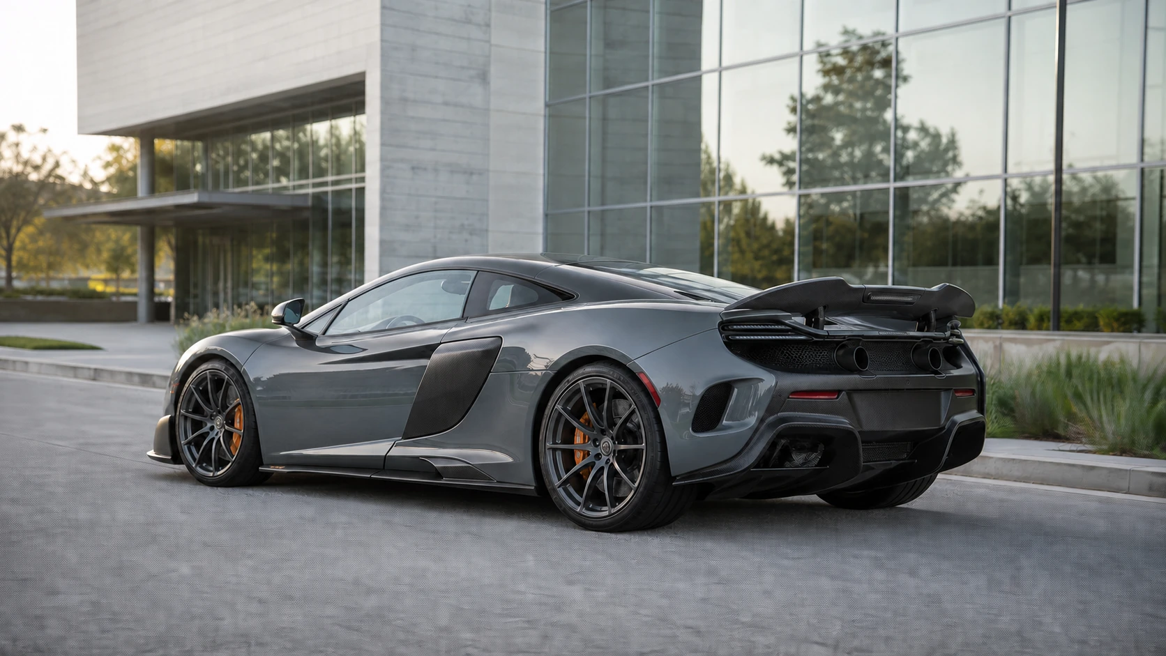 Gray McLaren 675LT outside a modern glass and concrete building