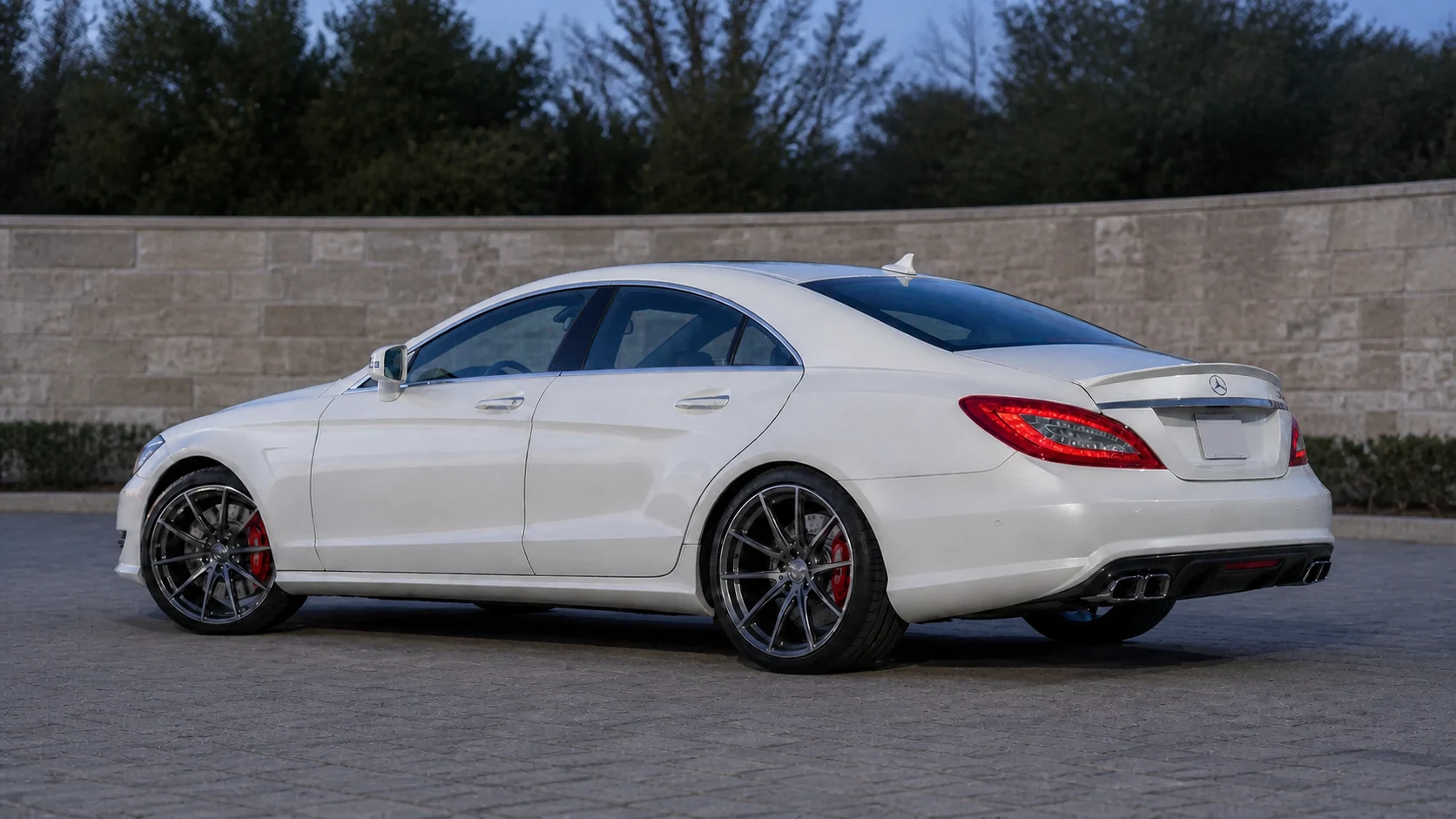White C218 Mercedes-AMG CLS63 parked beside a locality-neutral limestone wall