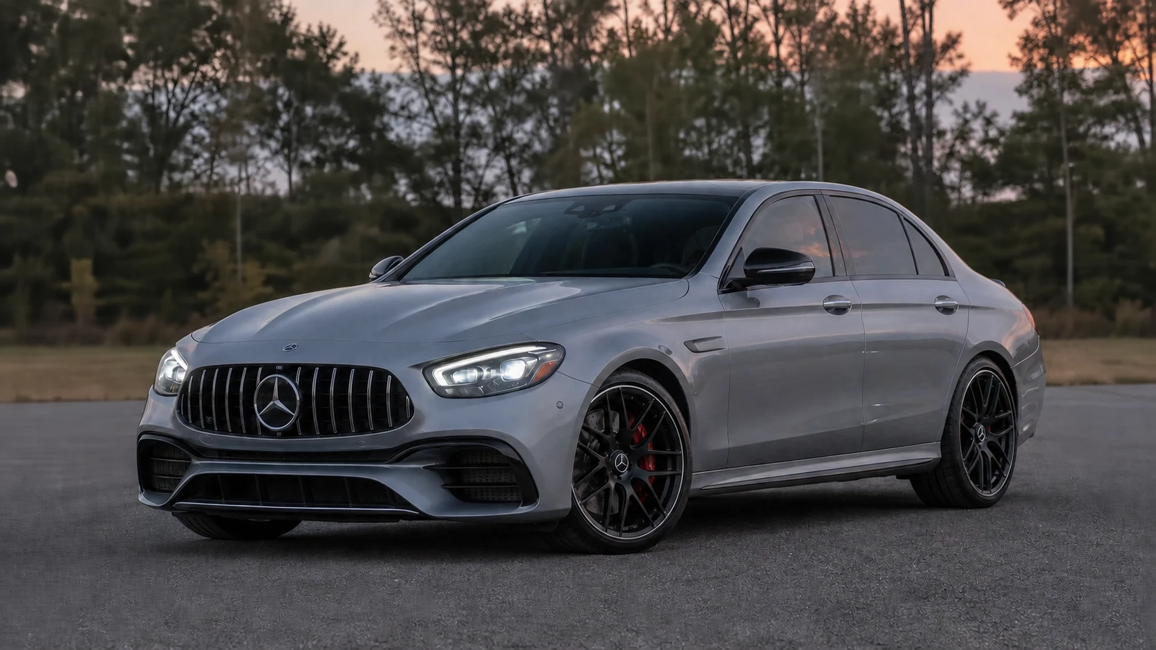 Silver W213 Mercedes-AMG E63 sedan with headlights on at blue hour
