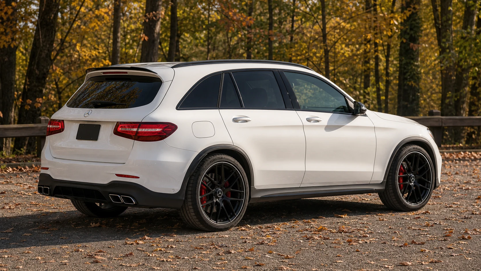 White X253 Mercedes-AMG GLC63 in a side-dominant rear three-quarter view among autumn trees
