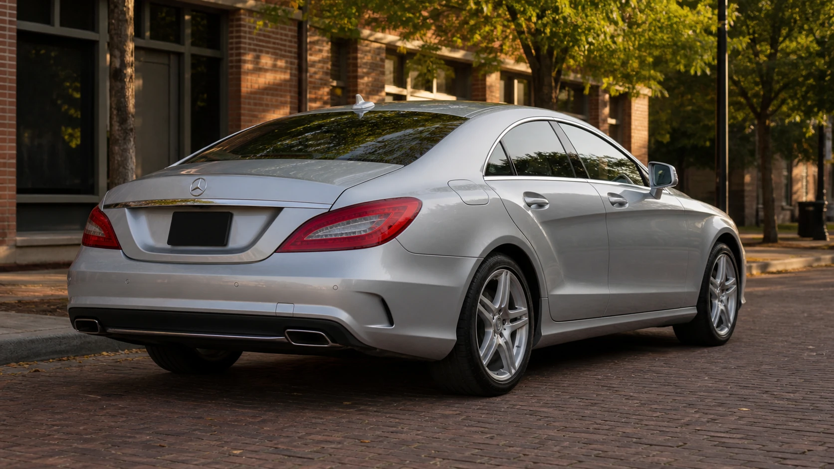 Silver C218 Mercedes CLS550 beside a tree-lined brick street