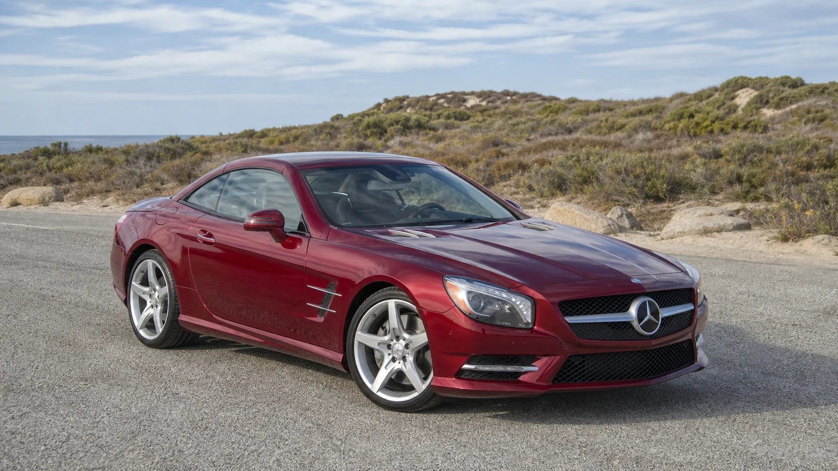 Dark red R231 Mercedes SL roadster beside pale coastal scrub