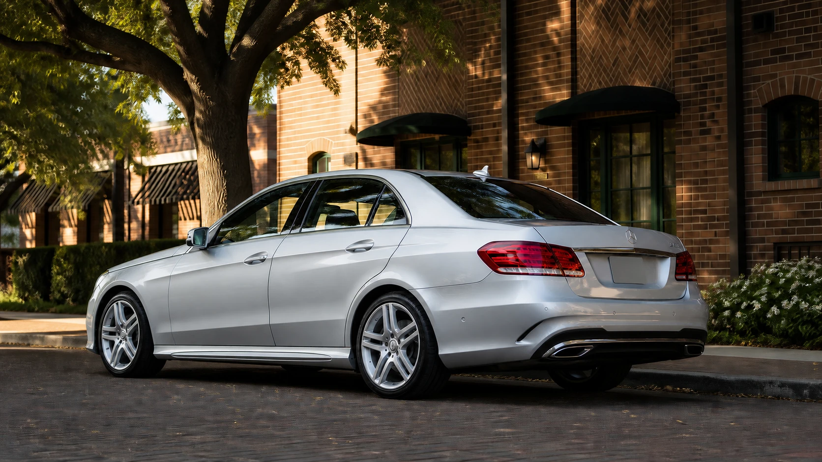 Silver W212 Mercedes E550 beside a tree-lined brick street