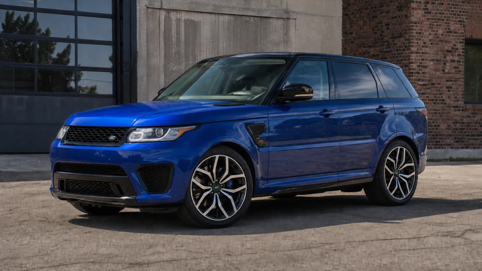 Blue pre-facelift L494 Range Rover Sport SVR outside an industrial building